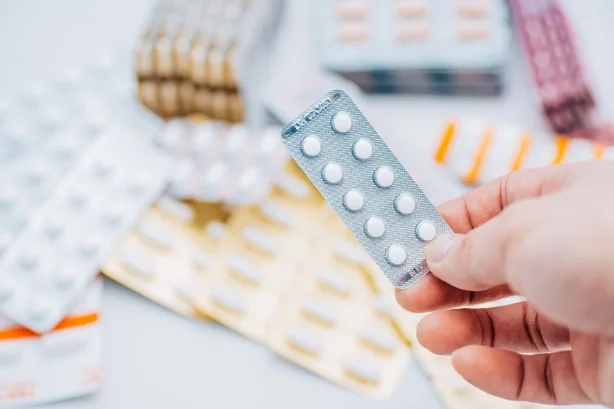 Photo:A bunch of pills are being held in the hand. Various medicines are placed in the background